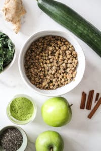 Flatlay image of lentil smoothie ingredients, including cooked lentils, apples, cucumber, cinnamon, ginger, matcha, and chia seeds.