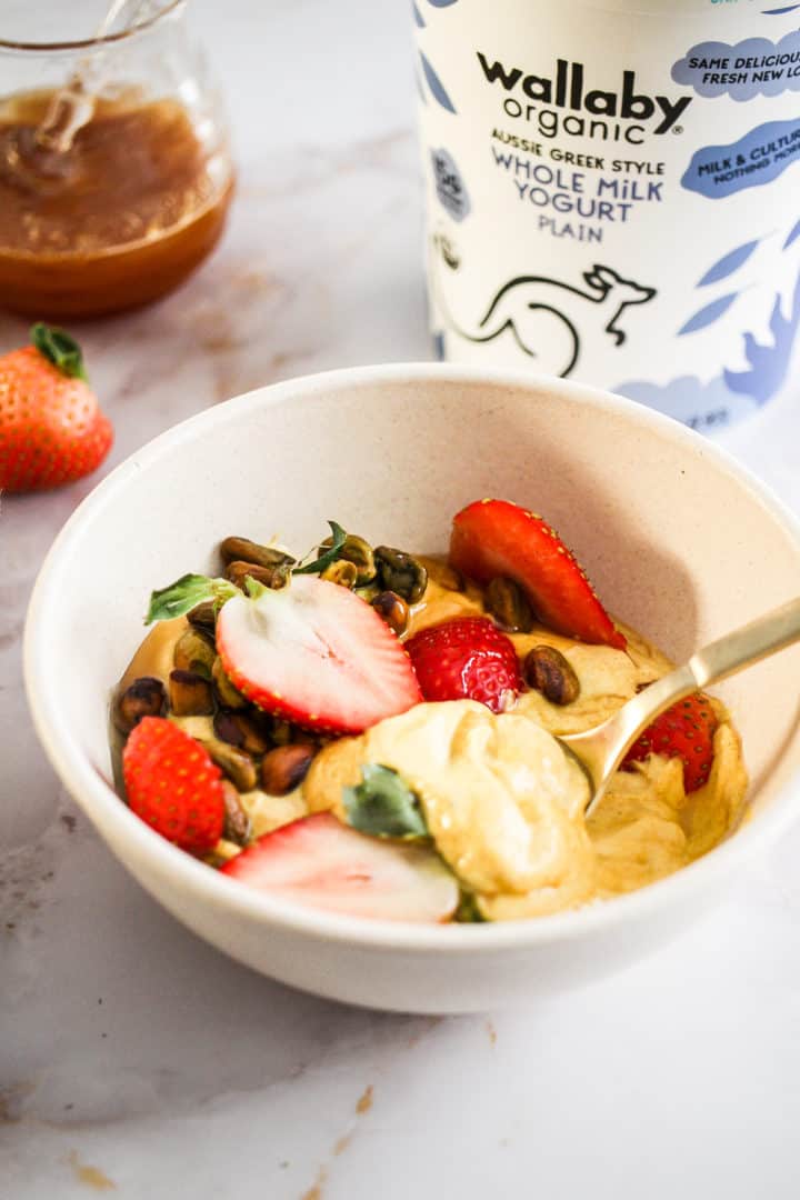 Closeup image of a turmeric yogurt bowl with a container of Wallaby Organic yogurt behind it.