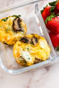 Baked egg cups in a meal prep container with strawberries.