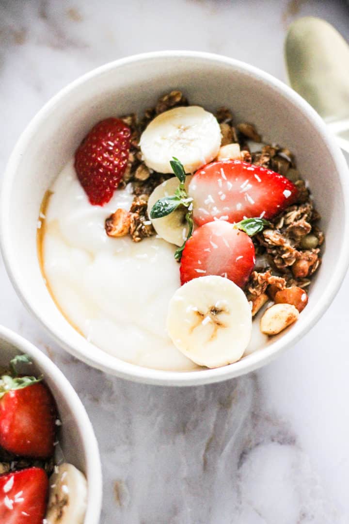 Closeup of a vegan granola bowl with macadamia nut granola, strawberries, and bananas.