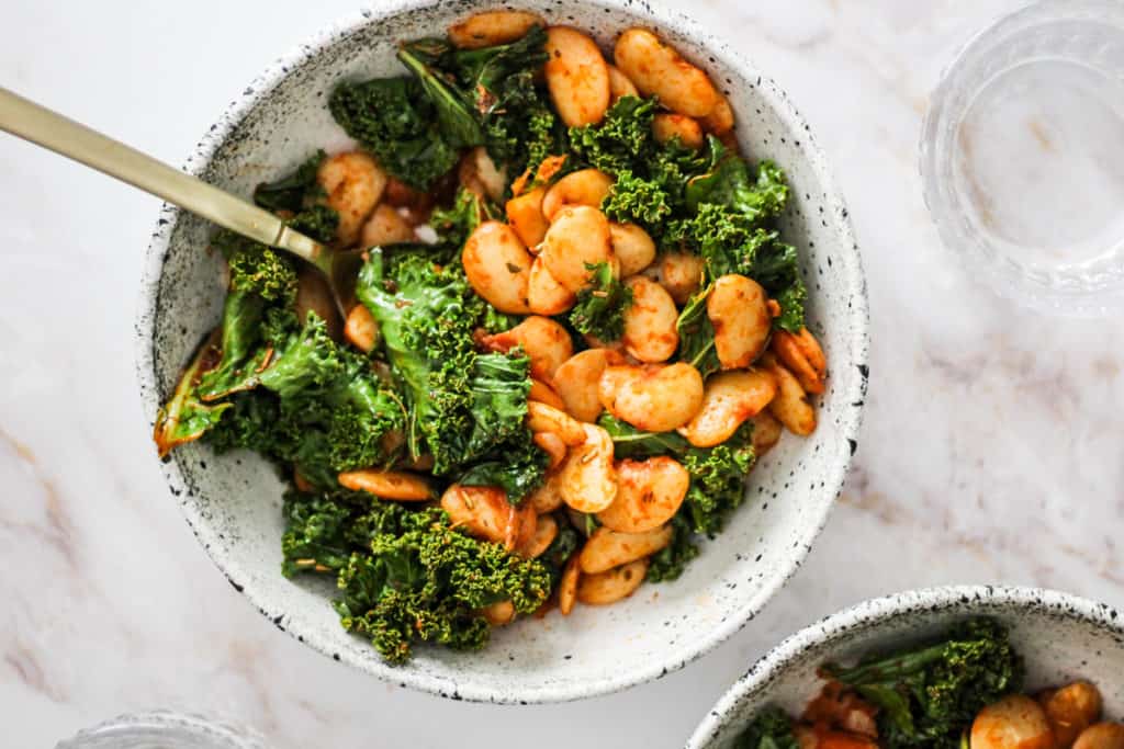 Horizontal image of lima beans and kale in a white bowl.