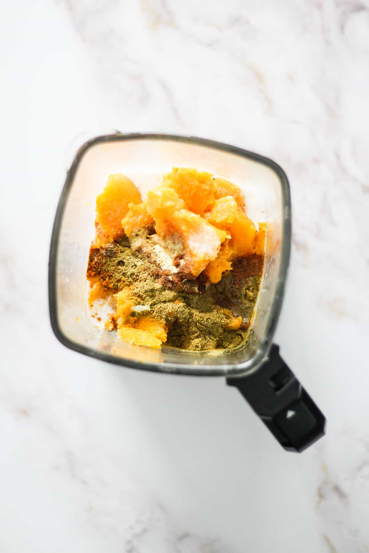 Butternut squash, coconut milk, and spices in a blender container.