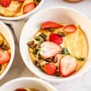 Golden yogurt bowl topped with strawberries, pistachios, and honey.