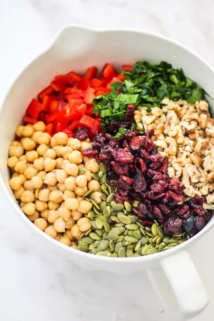 Chickpeas, pepitas, dry cranberries, walnuts, parsley, and diced bell pepper in a large mixing bowl.