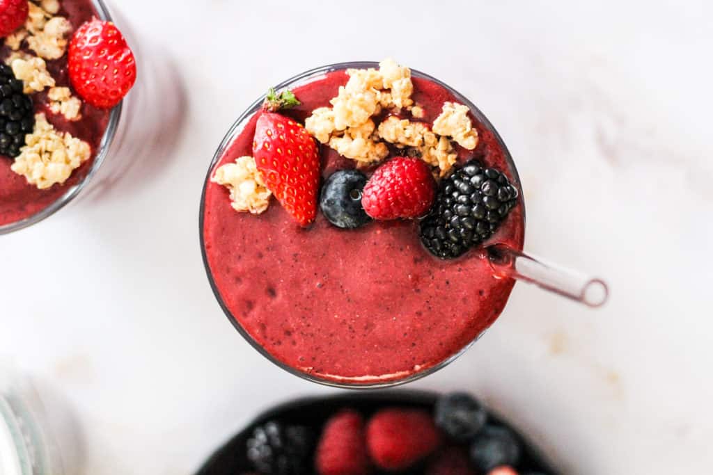 Horizontal image of a Berry Coconut Water Smoothie with berry and granola garnish.