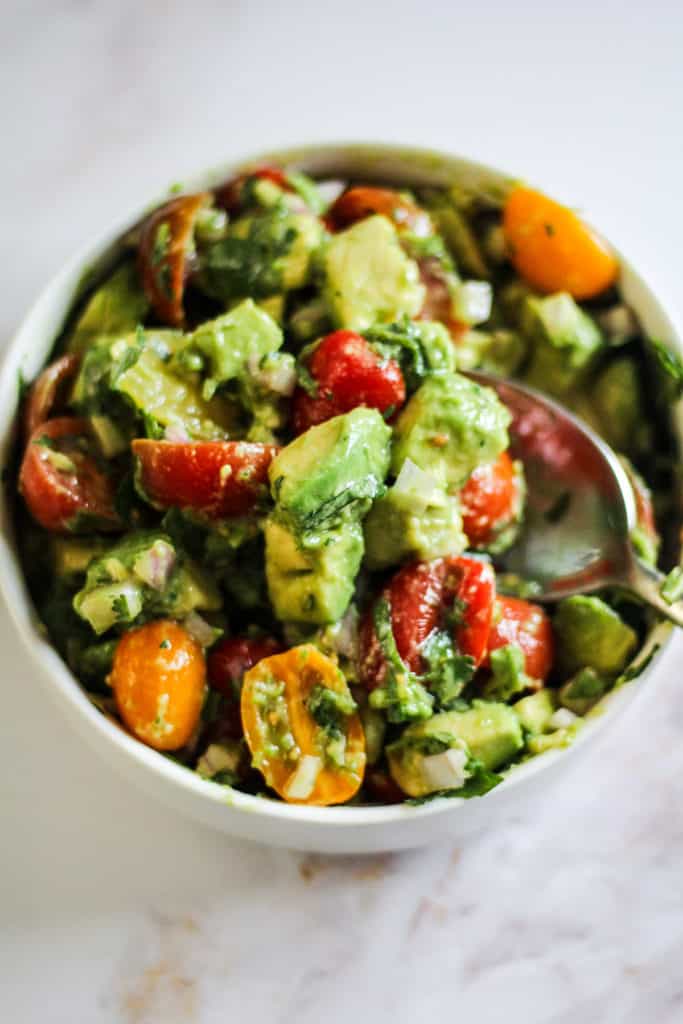Tomato and Avocado Salad with cilantro and lime in a white bowl.
