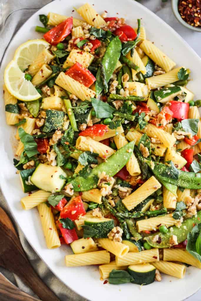 Closeup image of Vegan Pasta Primavera on a white serving platter.