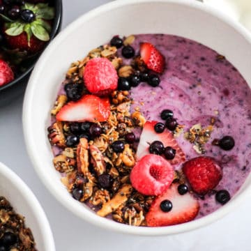 Purple yogurt bowl topped with granola and fresh fruit.