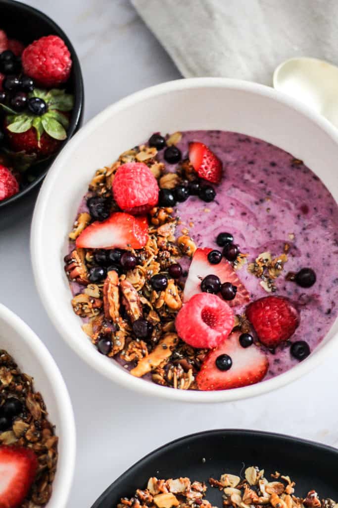 Closeup image of a Vegan Wild Blueberry Yogurt Alternative Bowl topped with granola and fresh berries.