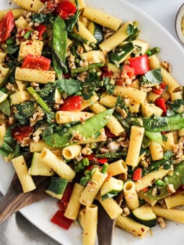 Platter of vegan pasta primavera with veggies and lemon cream sauce.