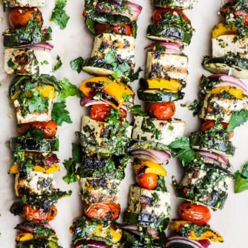 Grilled tofu and vegetable skewers with chmichurri sauce.