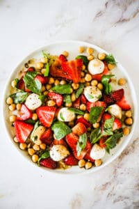 Summer Strawberry Salad with chickpeas, mozzarella, and basil on a white plate.