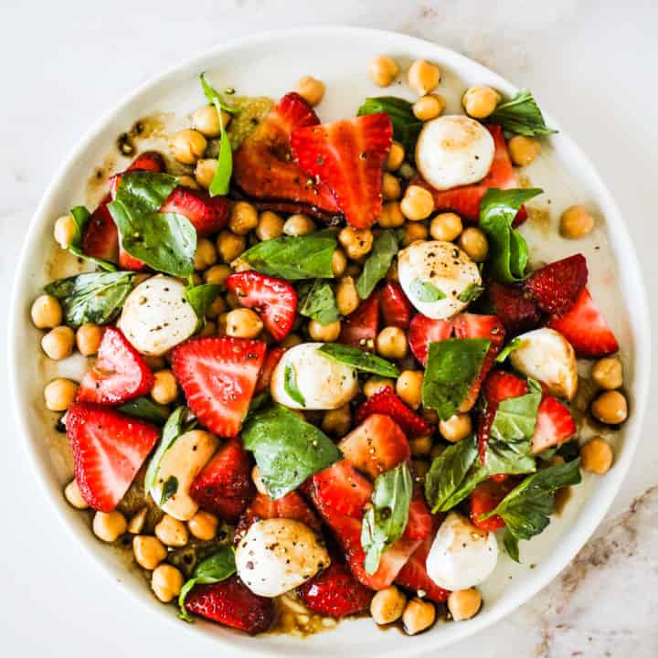 Summer Strawberry Salad with chickpeas, mozzarella, and basil on a white plate.