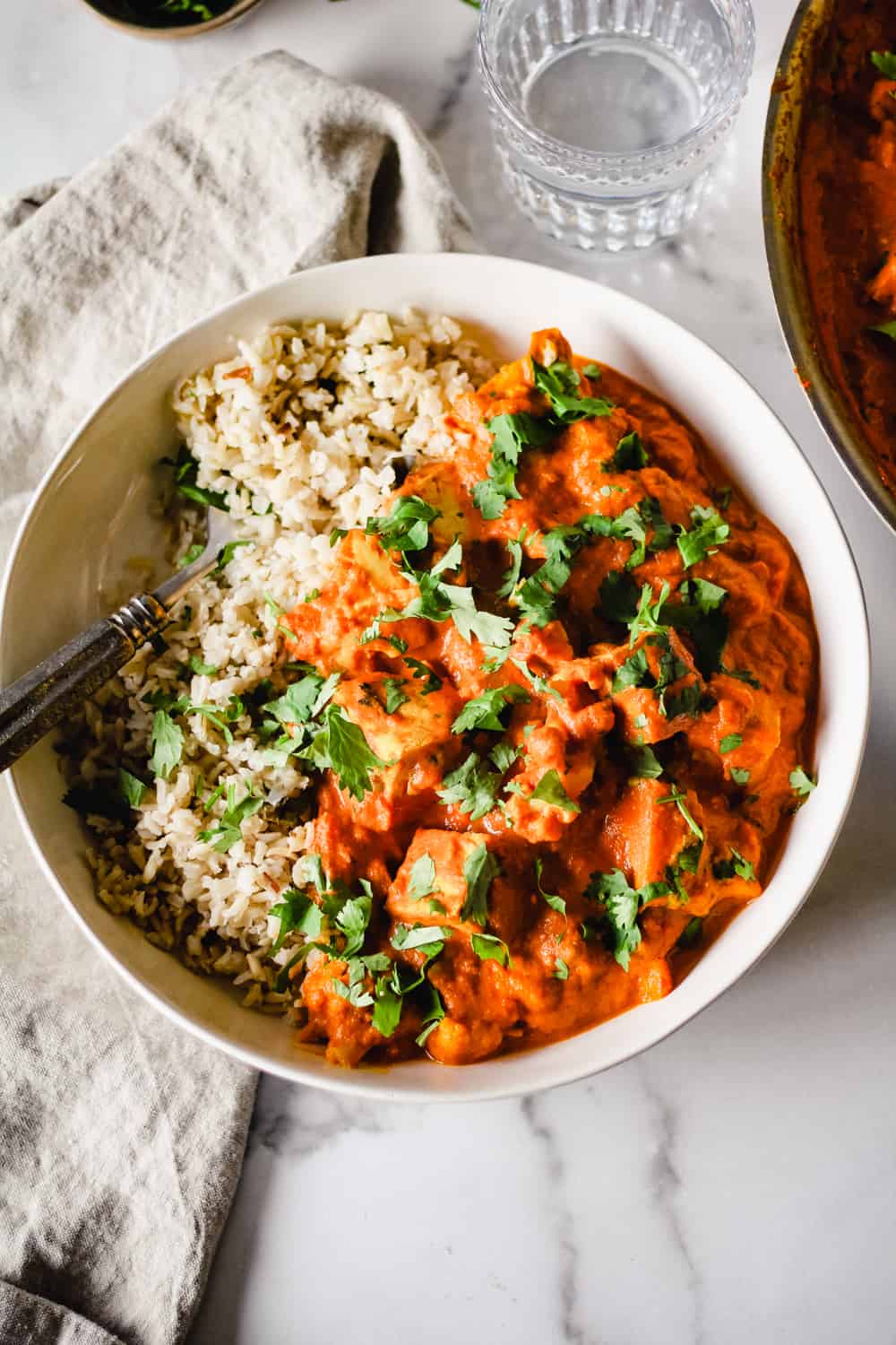 Overhead image of Vegan Tikka Masala in a white bowl with brown basmati rice and cilantro.
