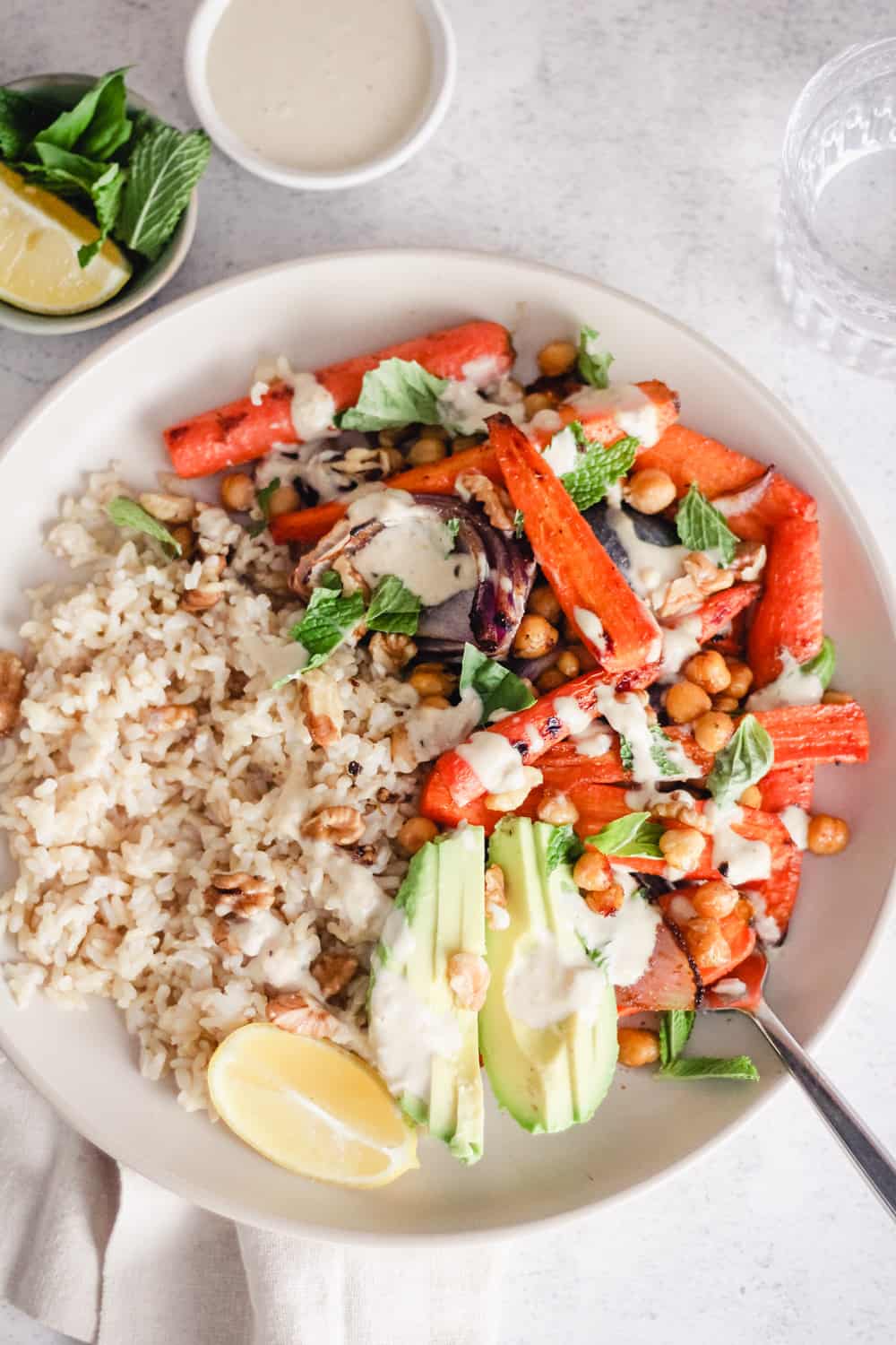 Overhead image of a vegan rice bowl with roasted vegetables, chickpeas, and avocado. 