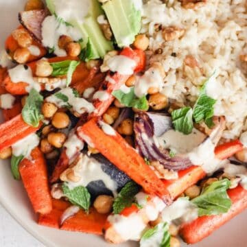 Vegetarian rice bowl with roasted carrots and chickpeas, avocado, and lemon tahini sauce.
