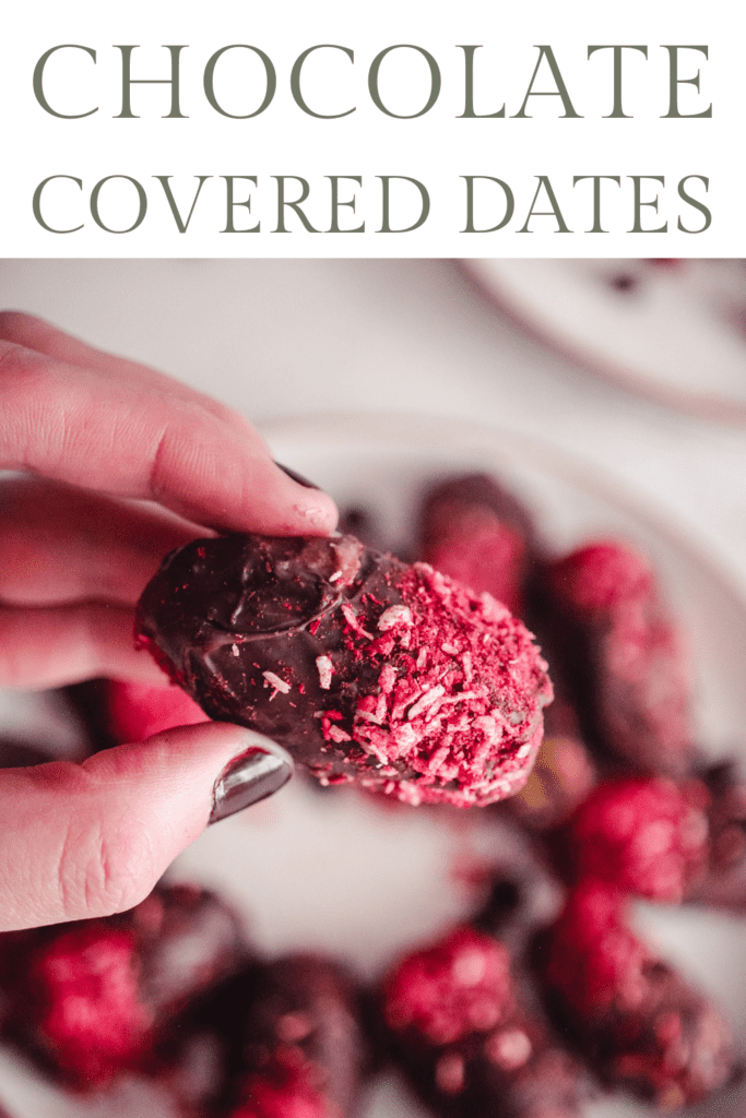 Closeup of a hand holding a chocolate date with raspberry and coconut topping. Text reads, "Chocolate Covered Dates."