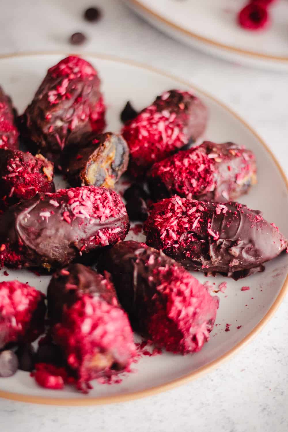 Dates covered in chocolate with raspberry and coconut powder.