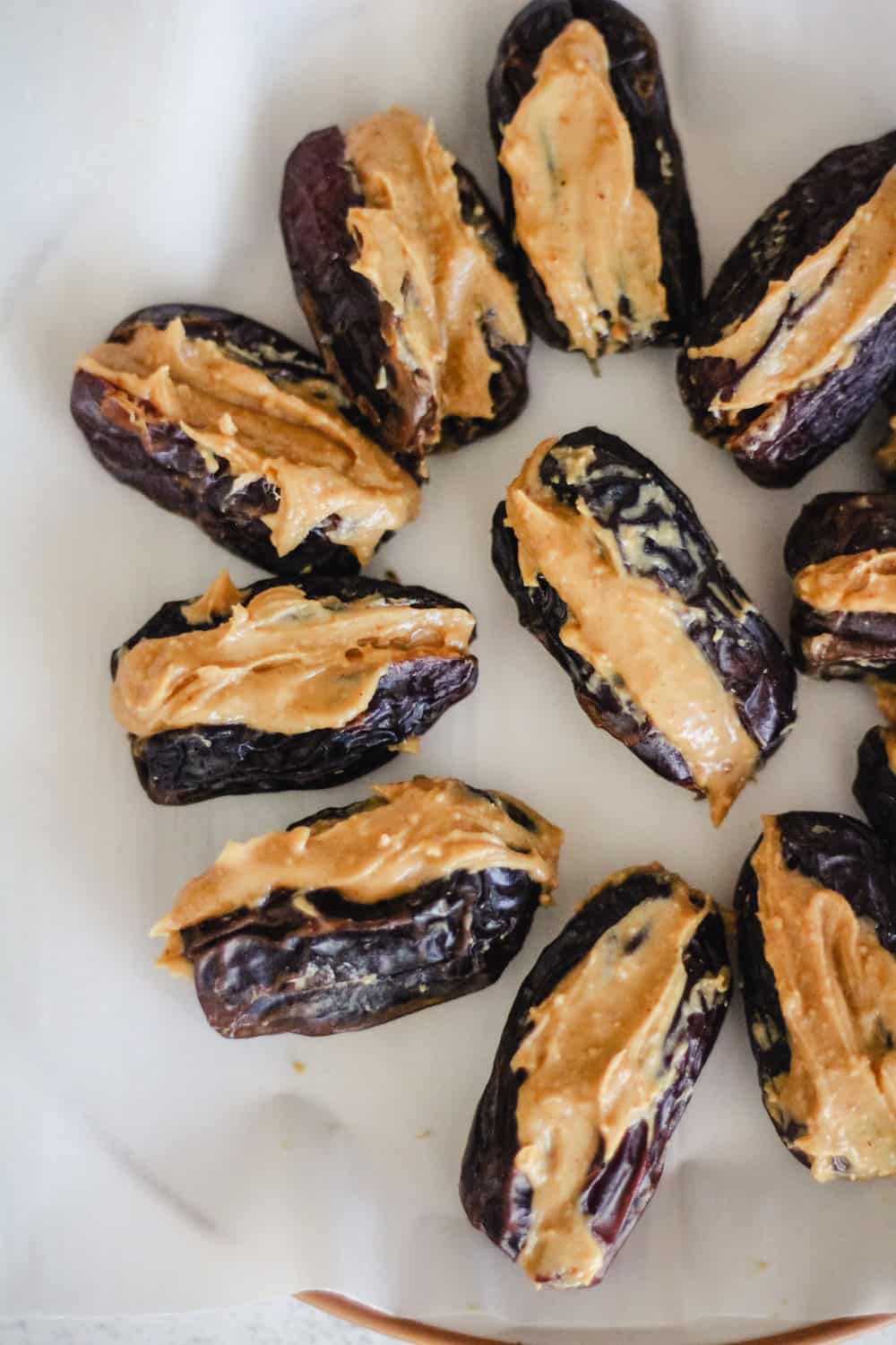 Dates stuffed with peanut butter on parchment paper.