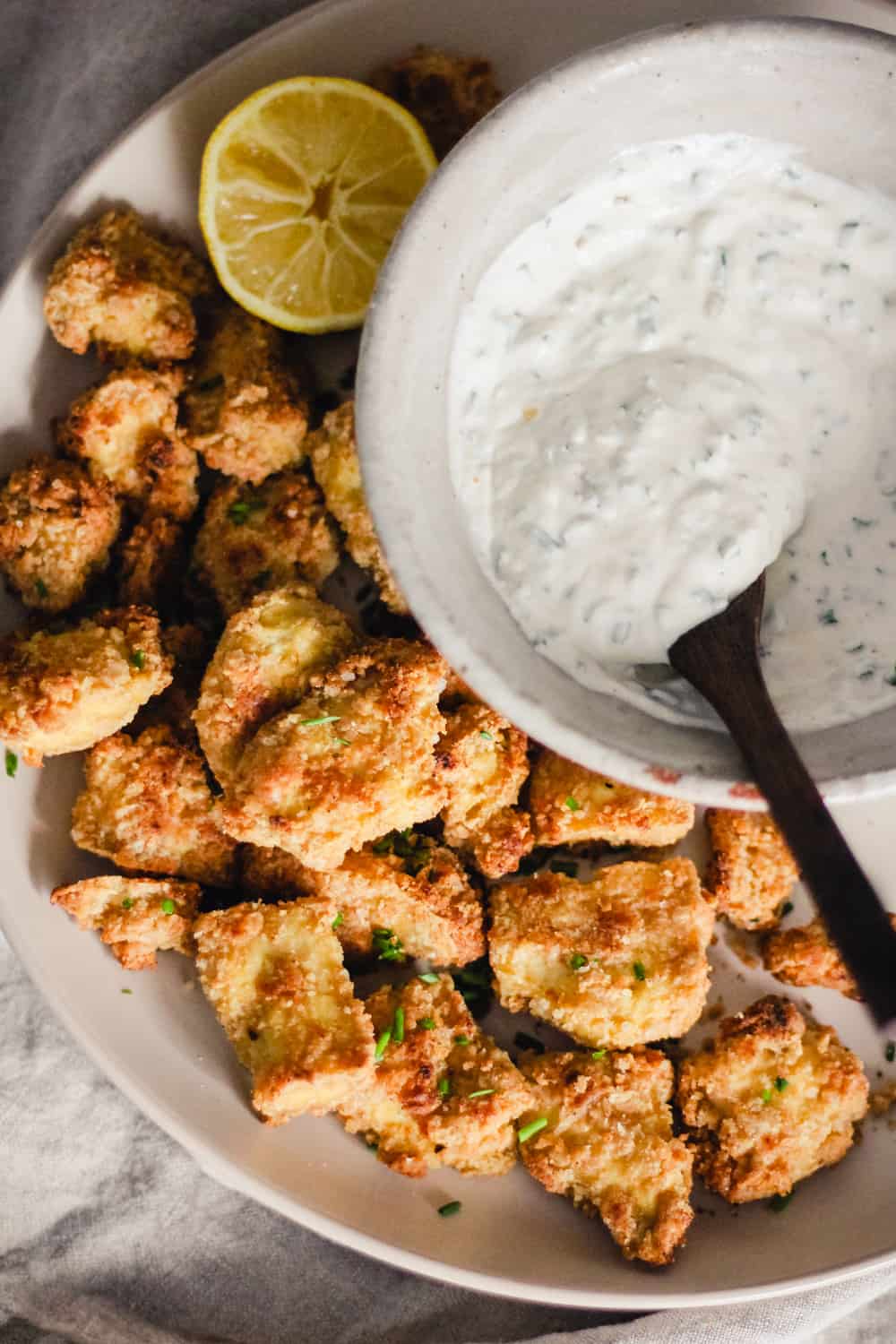 Crispy breaded tofu nuggets on a plate with a bowl of yogurt ranch dip.