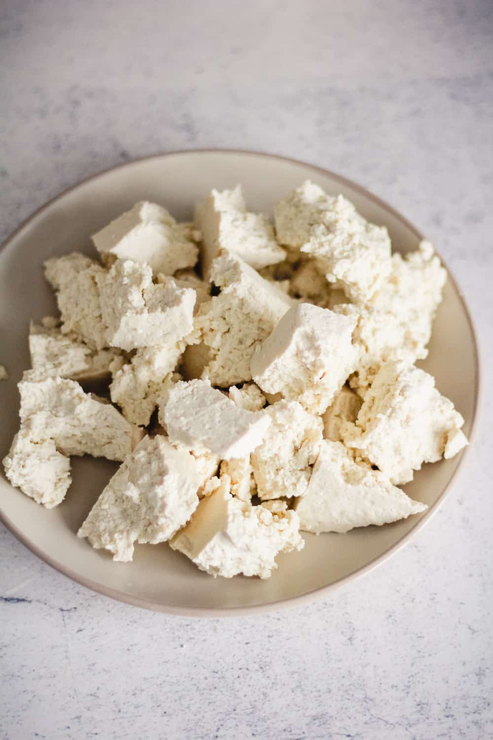Tofu torn into bite sized pieces on a plate.