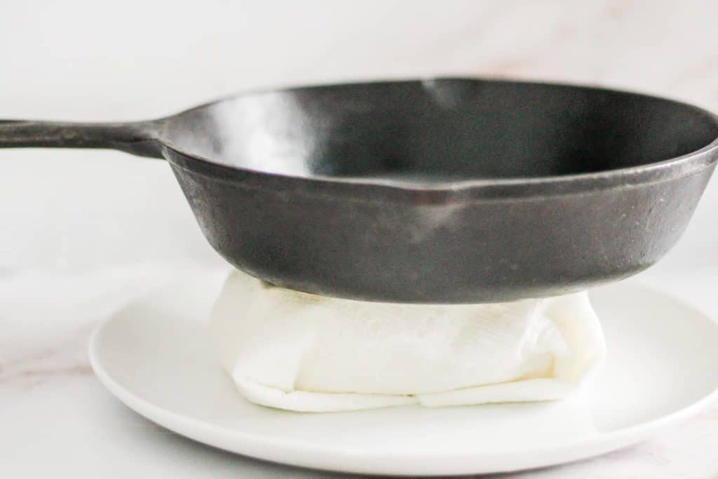 Pressing tofu with a cast iron skillet on top.