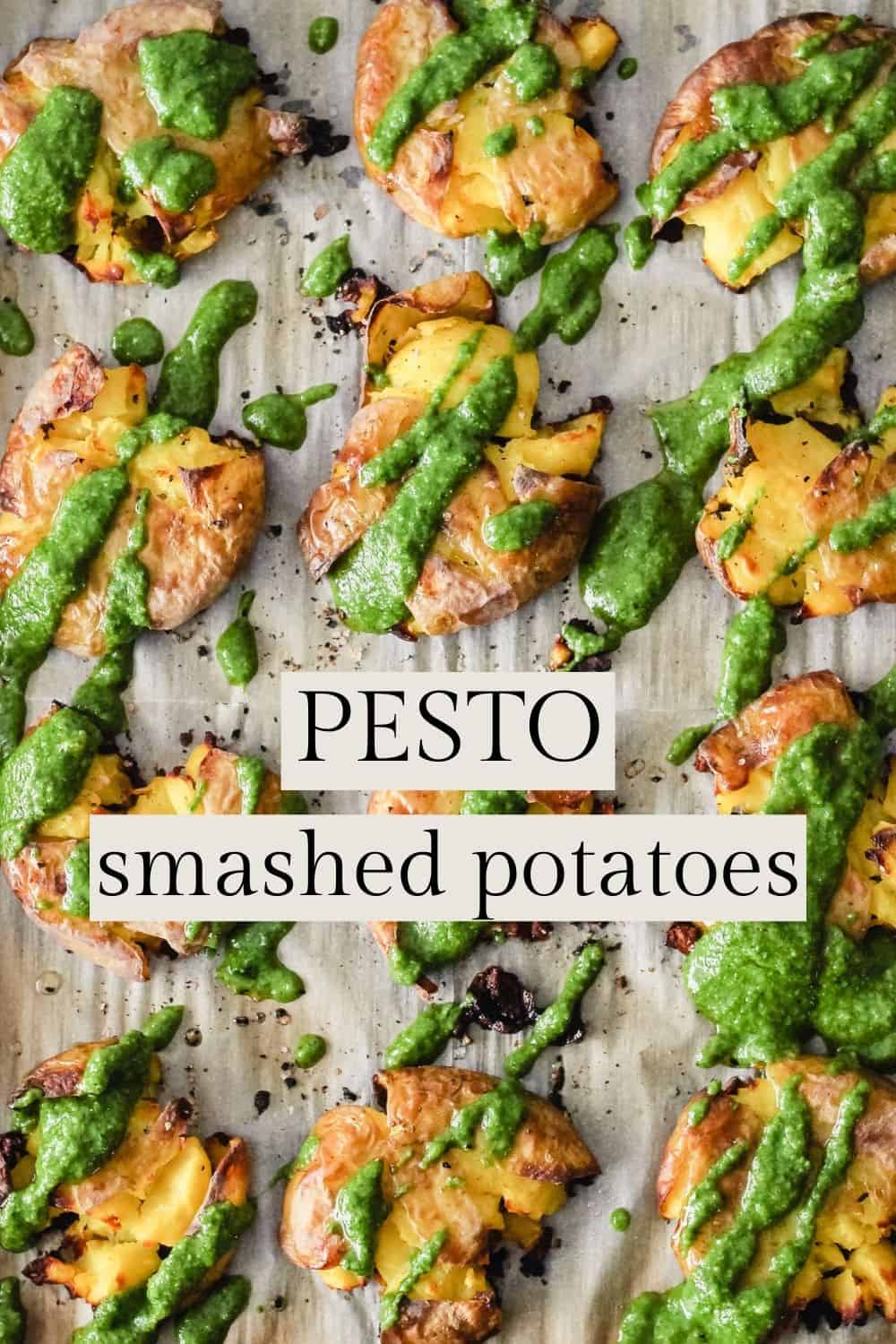 Smashed potatoes with pesto sauce on a baking sheet. Text reads, "Pesto Smashed Potatoes."