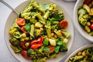 Plate of pesto pasta with vegetables and chickpeas.