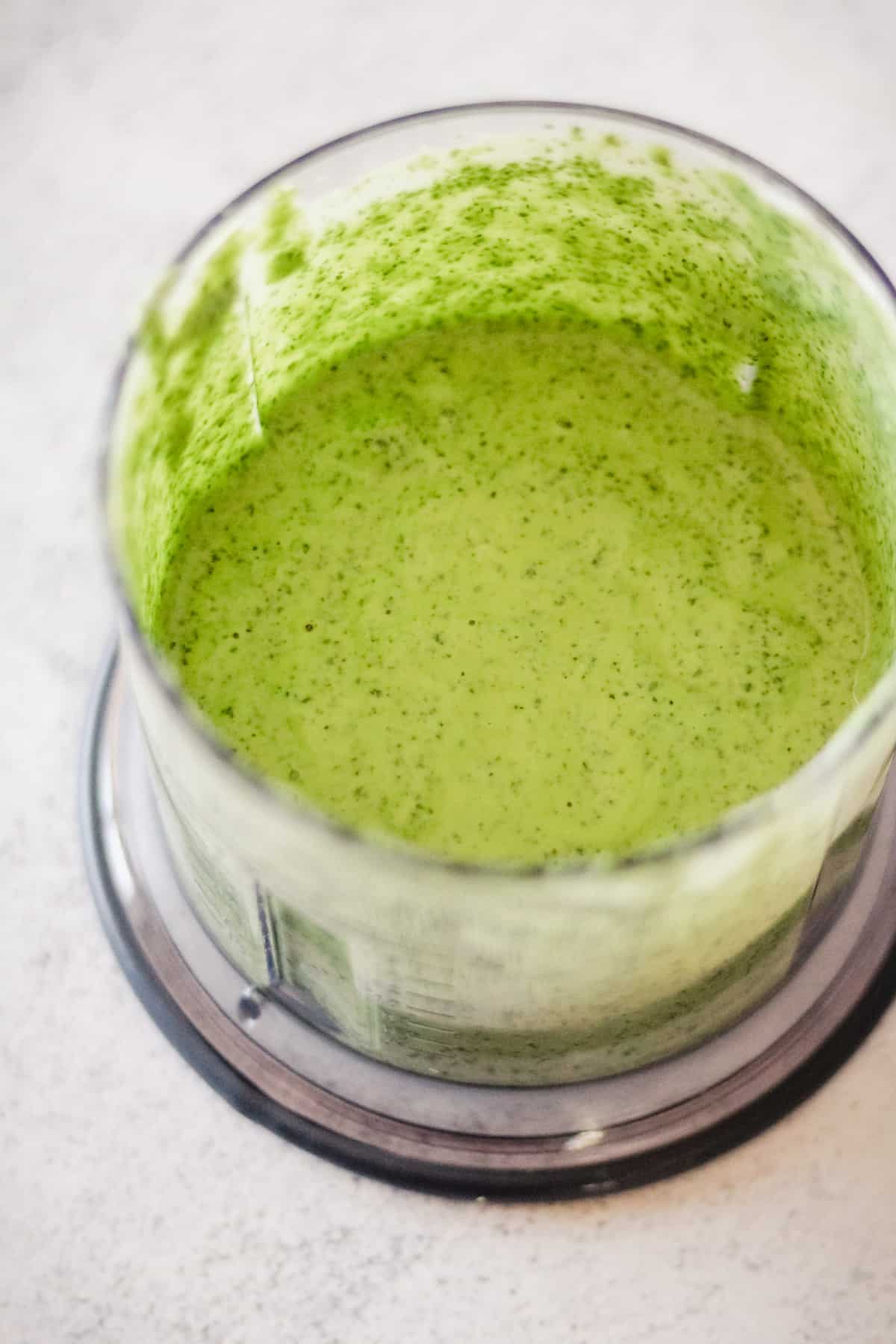 Process shot with blended green goddess dressing in a food processor.