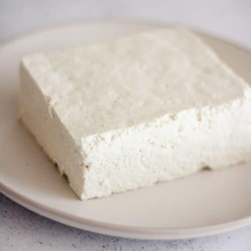 Square image of a block of pressed tofu on a plate.