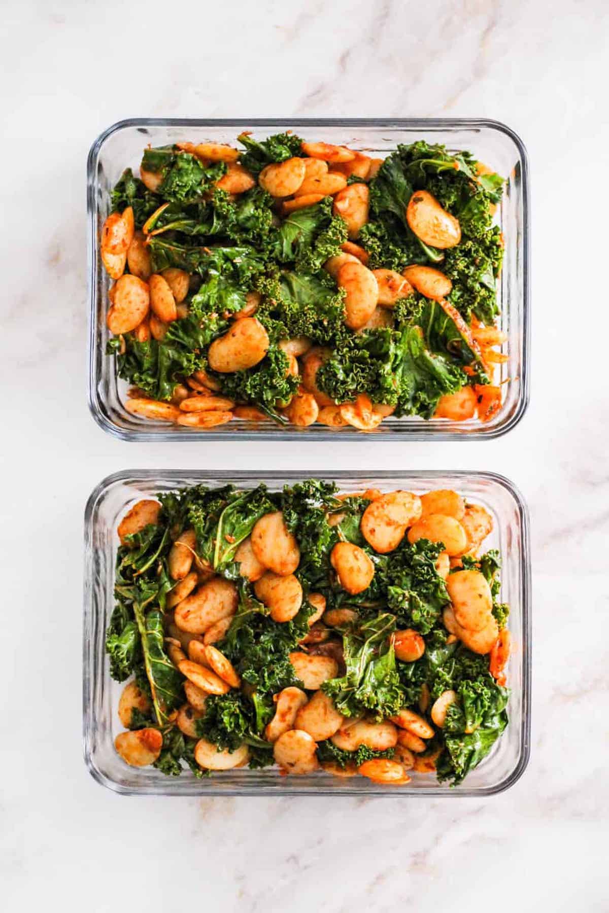 Two glass meal prep containers with butter beans and greens.