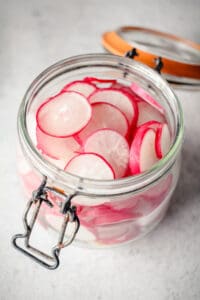 Sliced red radishes in a jar.