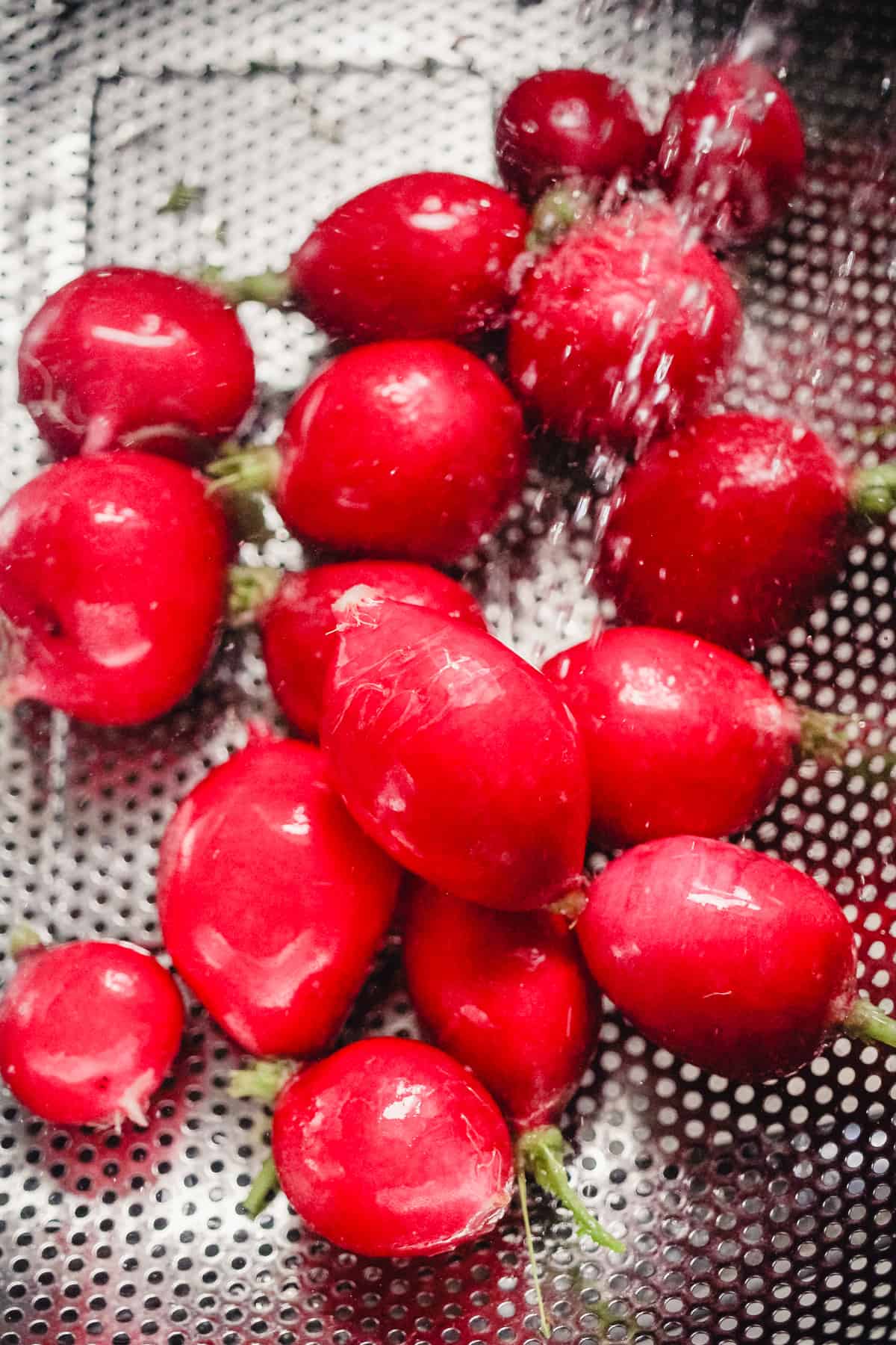 Washing radishes in a colander in the sink.