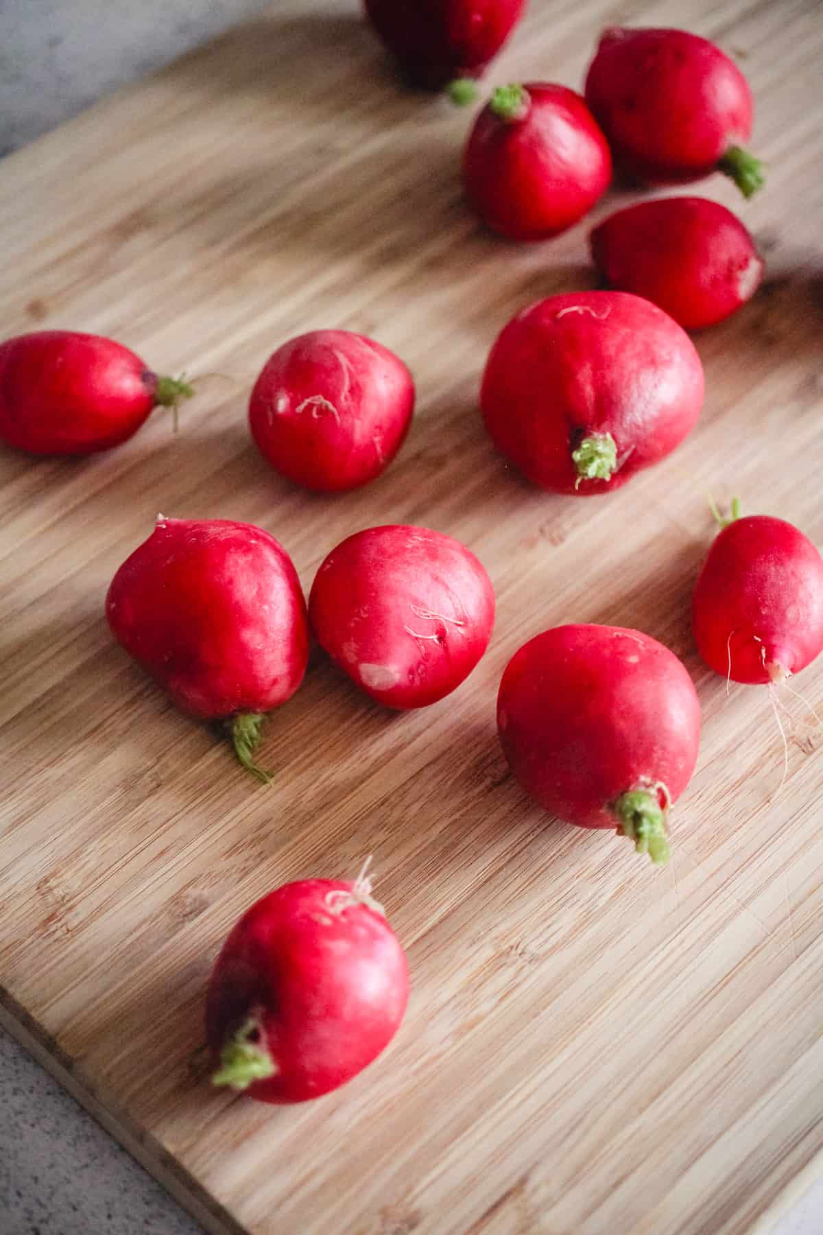 Whole red radishes on a cutting board.