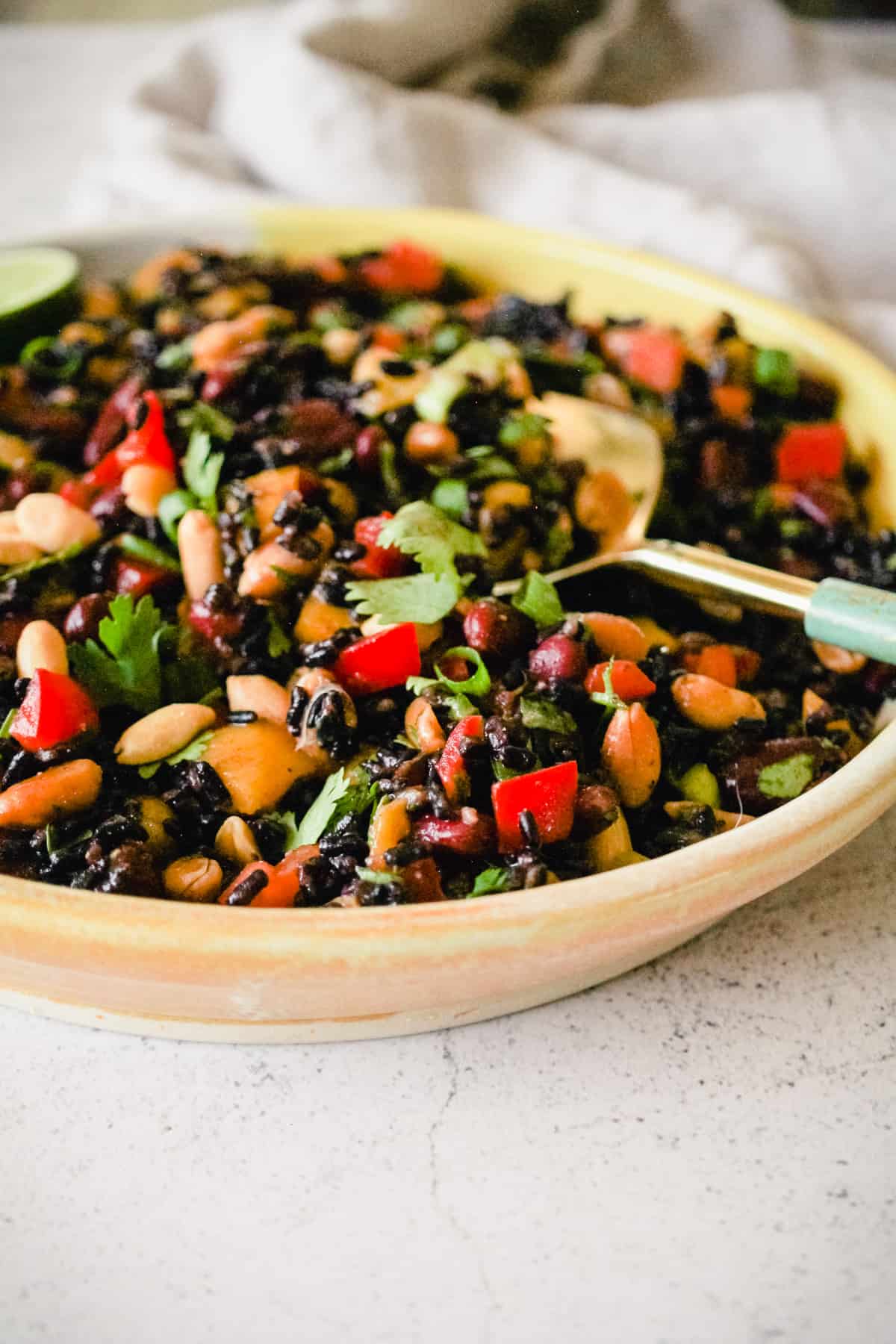 Black rice and bean salad in a yellow ceramic serving dish.