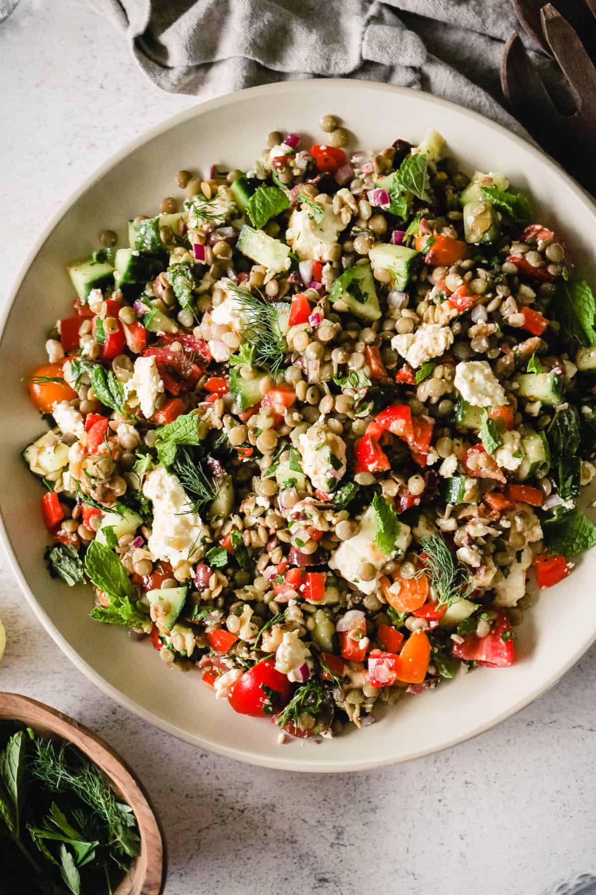 Mediterranean lentil salad with feta and fresh herbs on a white plate.