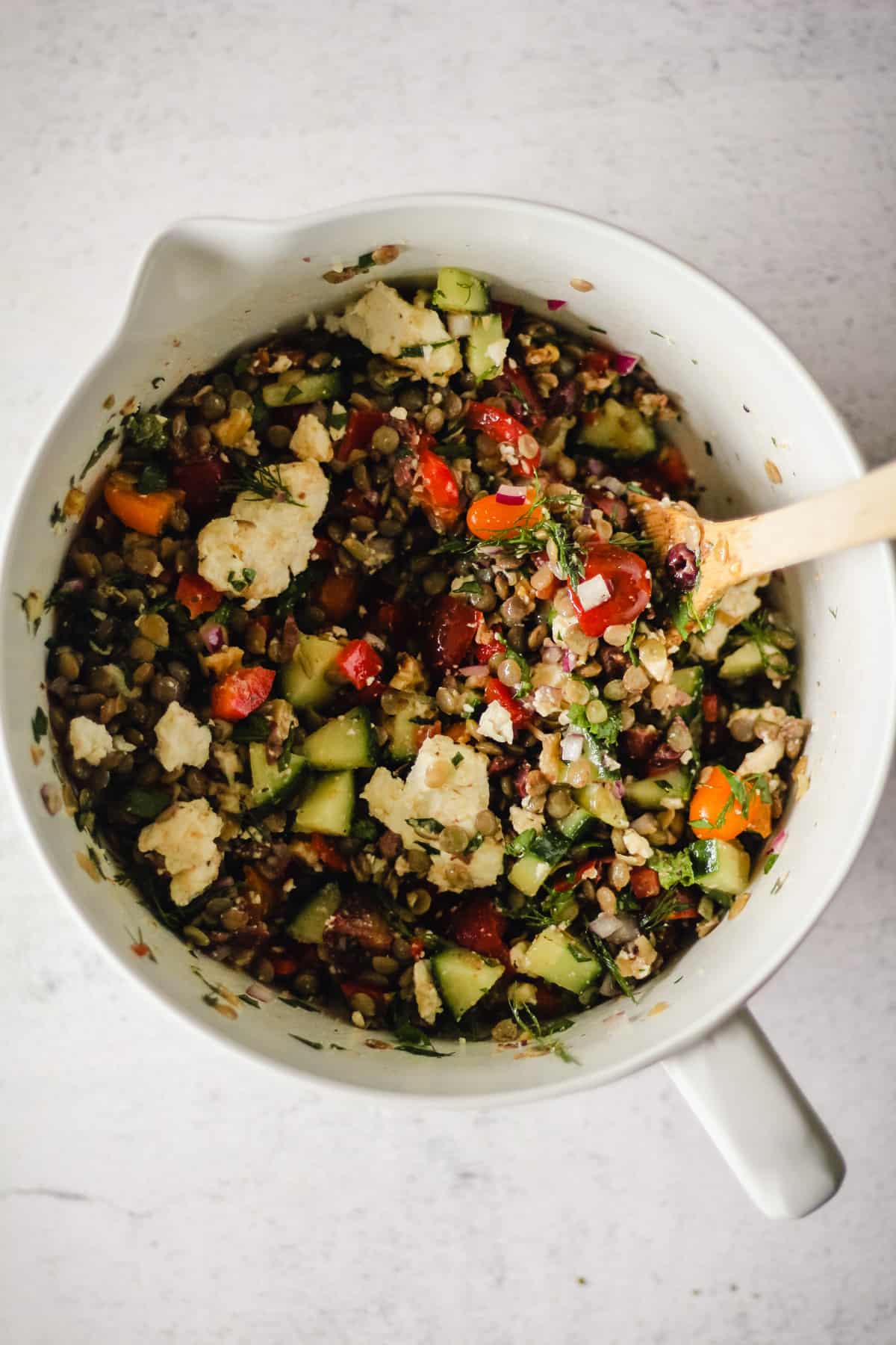 Adding feta cheese to the lentil salad.