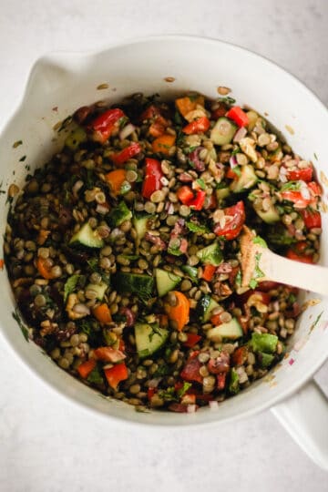 Stirring lentil salad with Greek dressing.