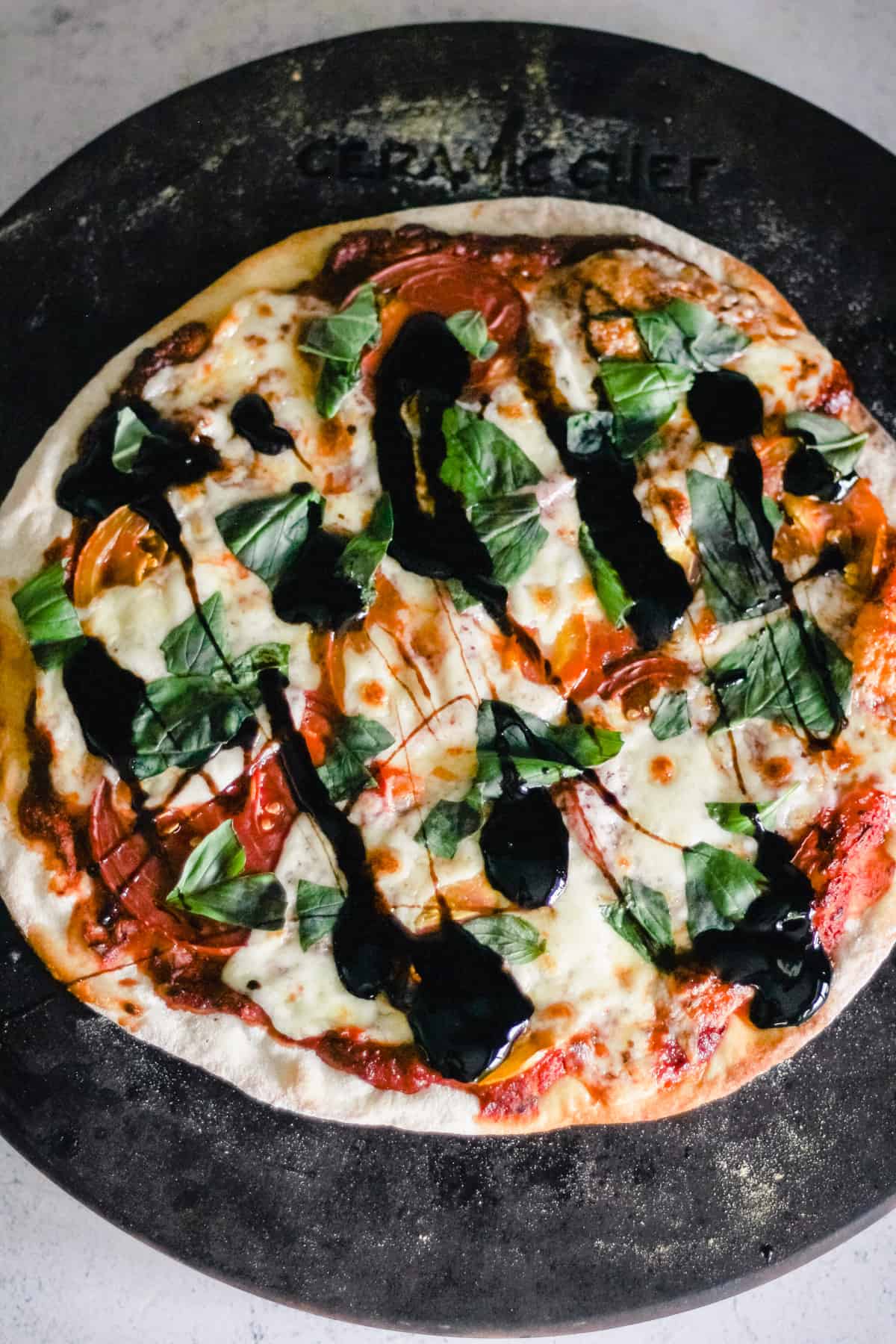 Caprese pizza with balsamic glaze on a pizza stone