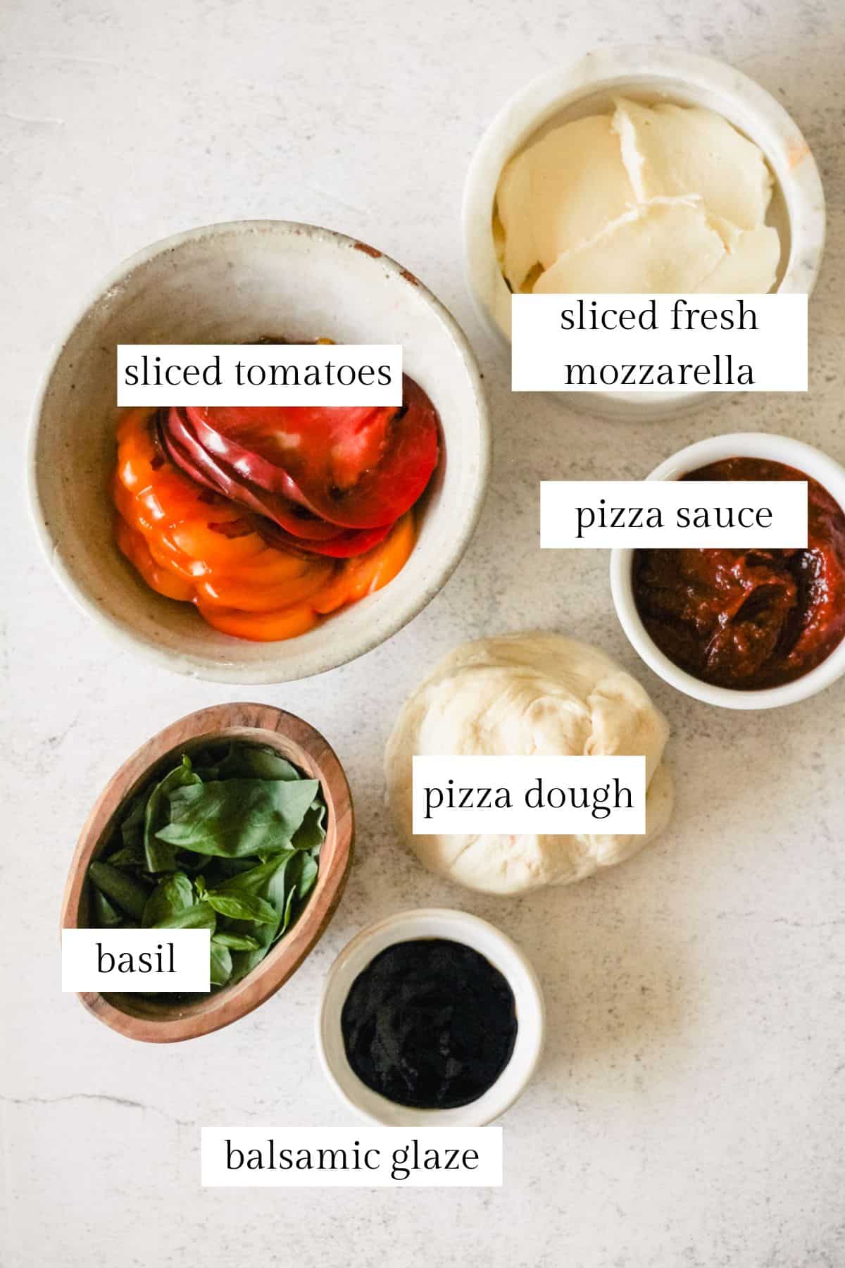 Labeled ingredients for making caprese pizza.
