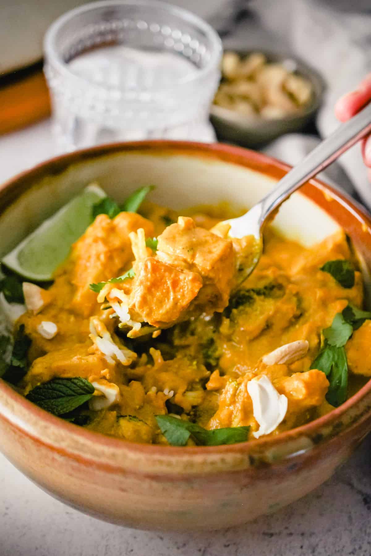 A fork with Tofu Pumpkin Curry held over the bowl.