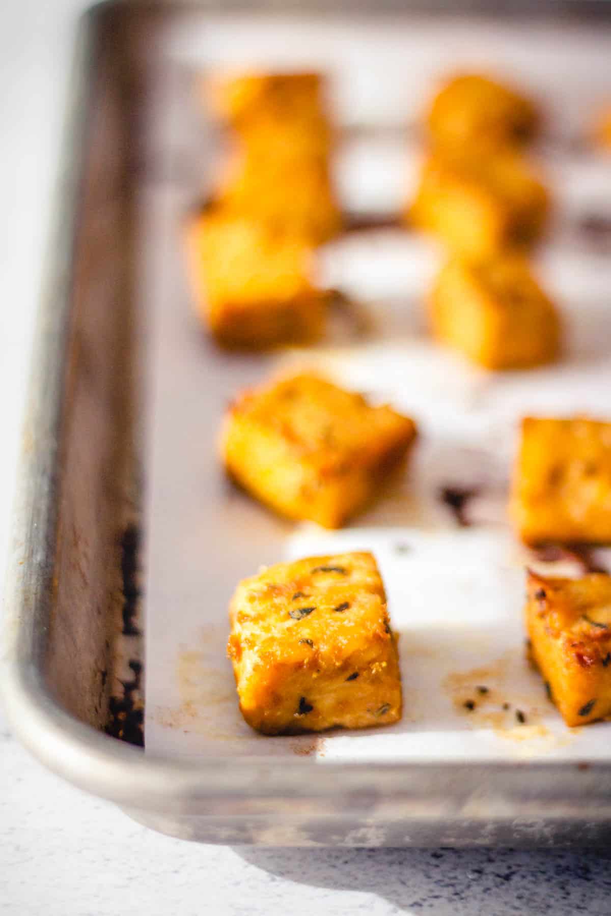 Marinated baked tempeh cubes on a baking sheet.