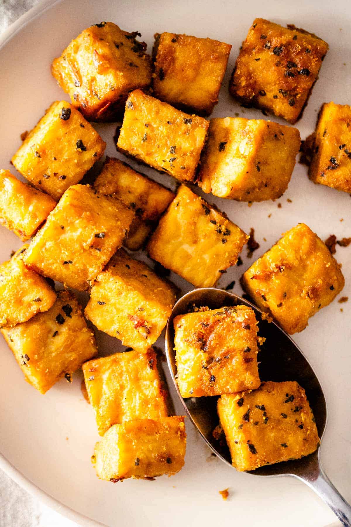 Marinated baked tempeh cubes on a plate.
