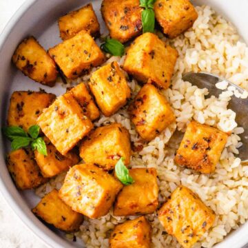 Marinated and baked tempeh cubes in a dish with rice.