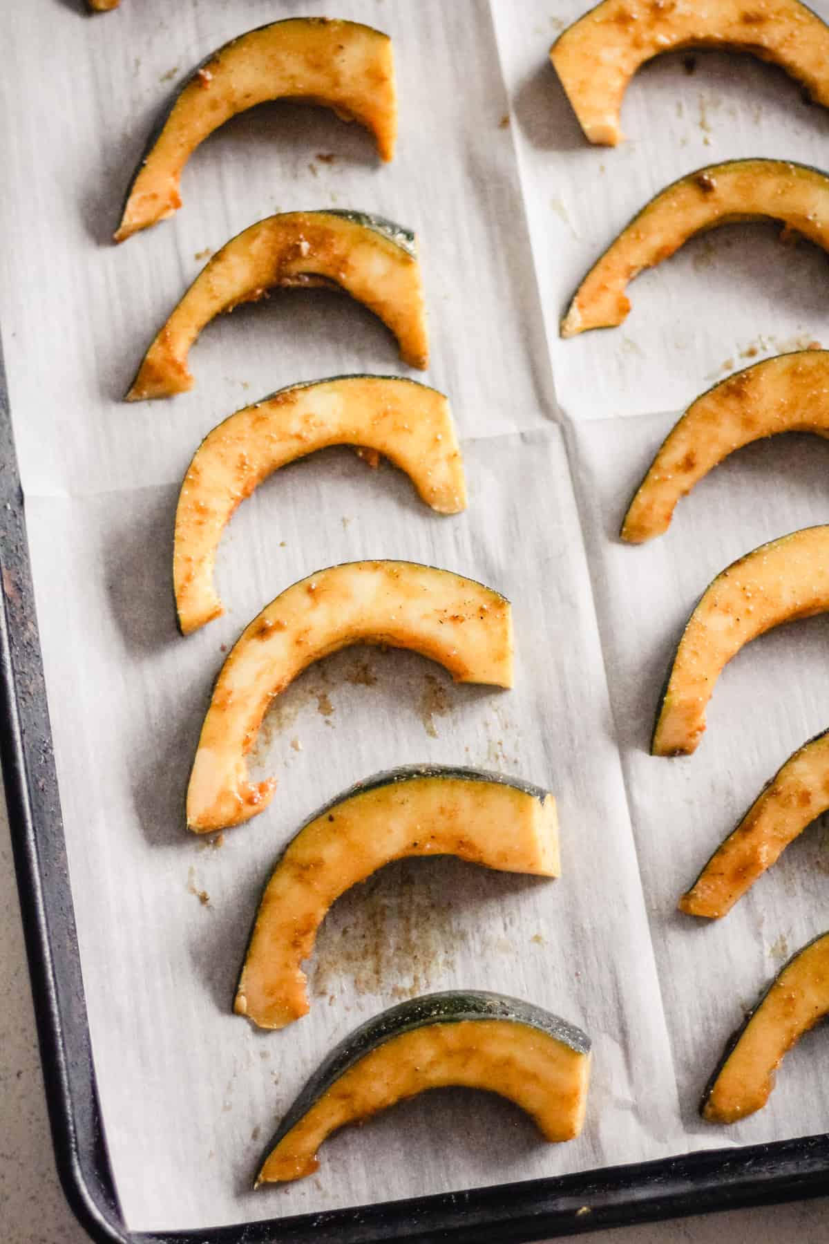 Uncooked squash wedges on a baking sheet.