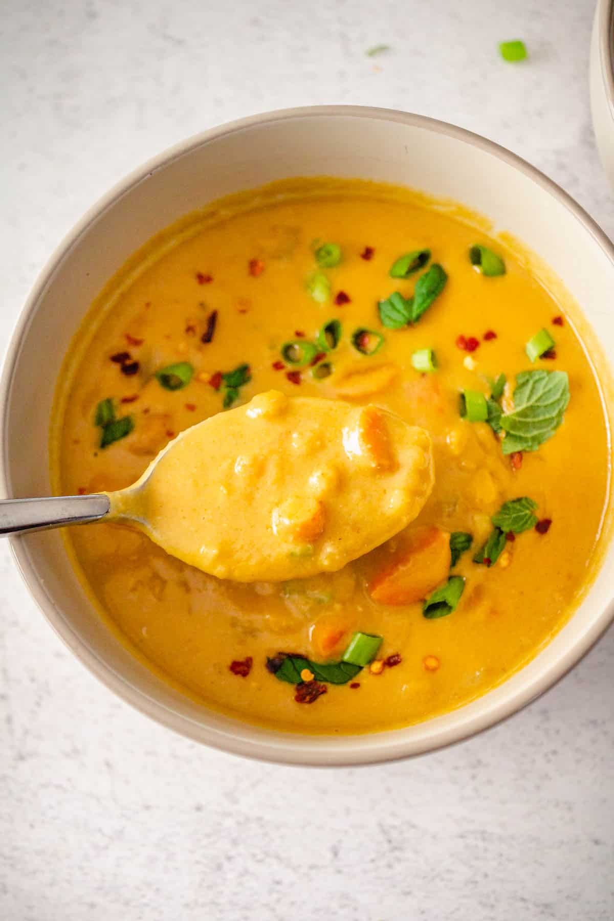 Spoonful of Carrot Lentil Soup over bowl.