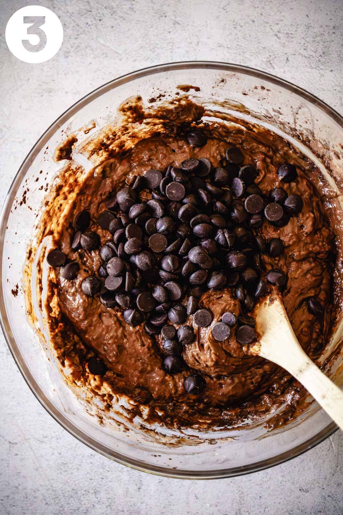 Bowl of chocolate muffin batter with chocolate chips on top.