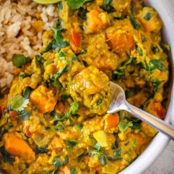 Closeup of red lentil curry with sweet potatoes and spinach.