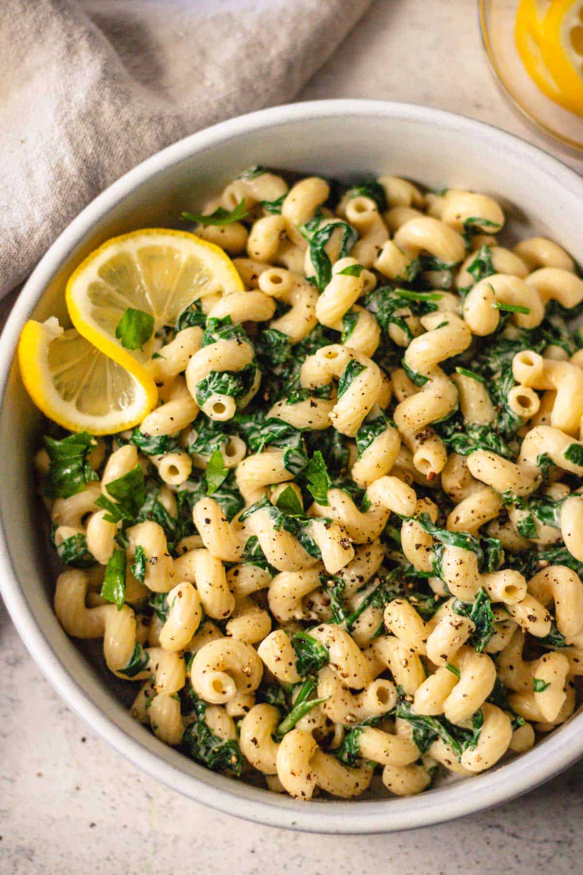 Creamy pasta with vegan lemon tahini pasta sauce and spinach in a ceramic pasta bowl.