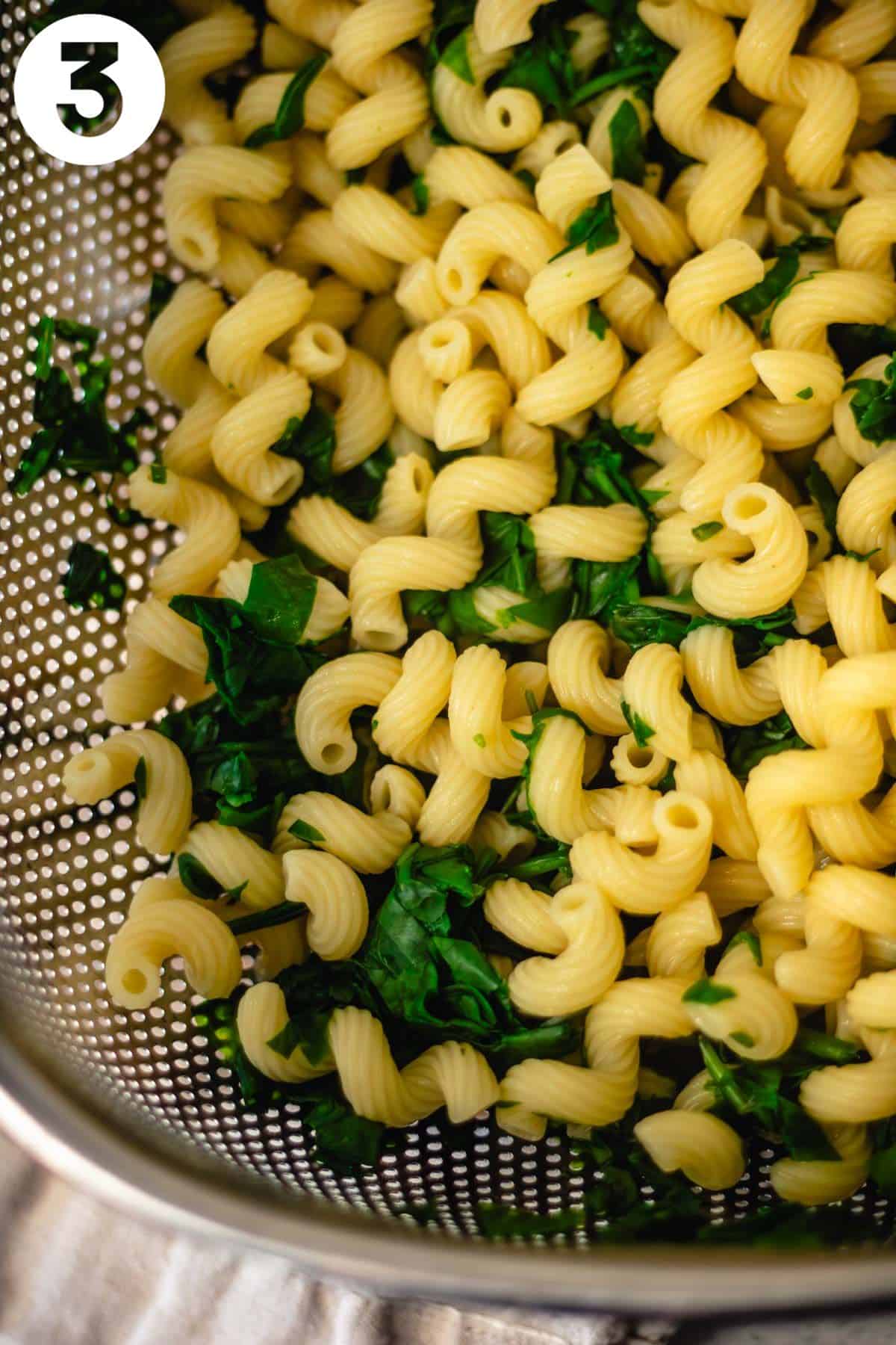 Step 3 is shown draining the pasta and spinach in a colander. The photo is labeled with a "3" in the upper left corner.